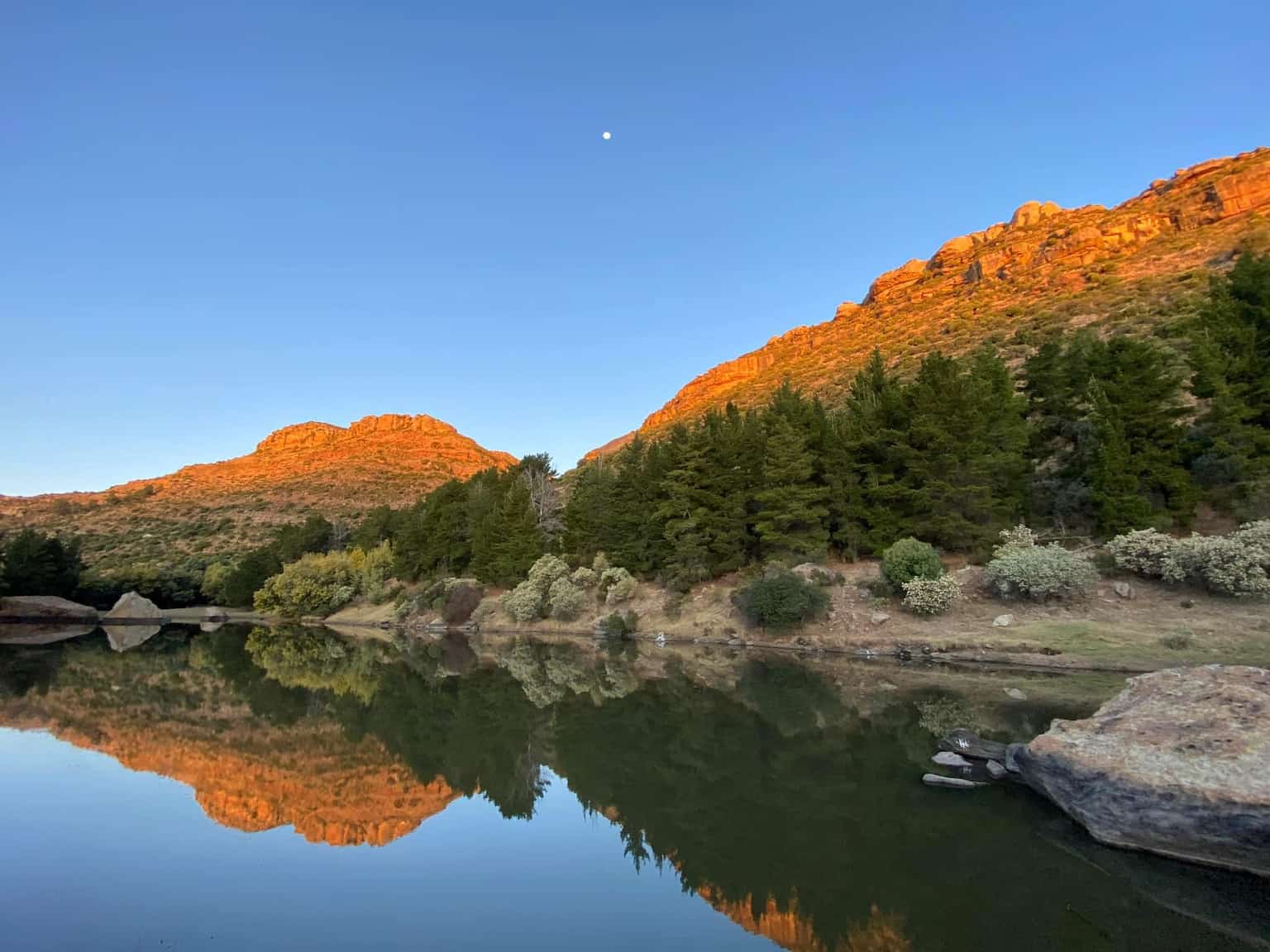 Majestic mountains of Lesotho reflected in calm waters at golden hour