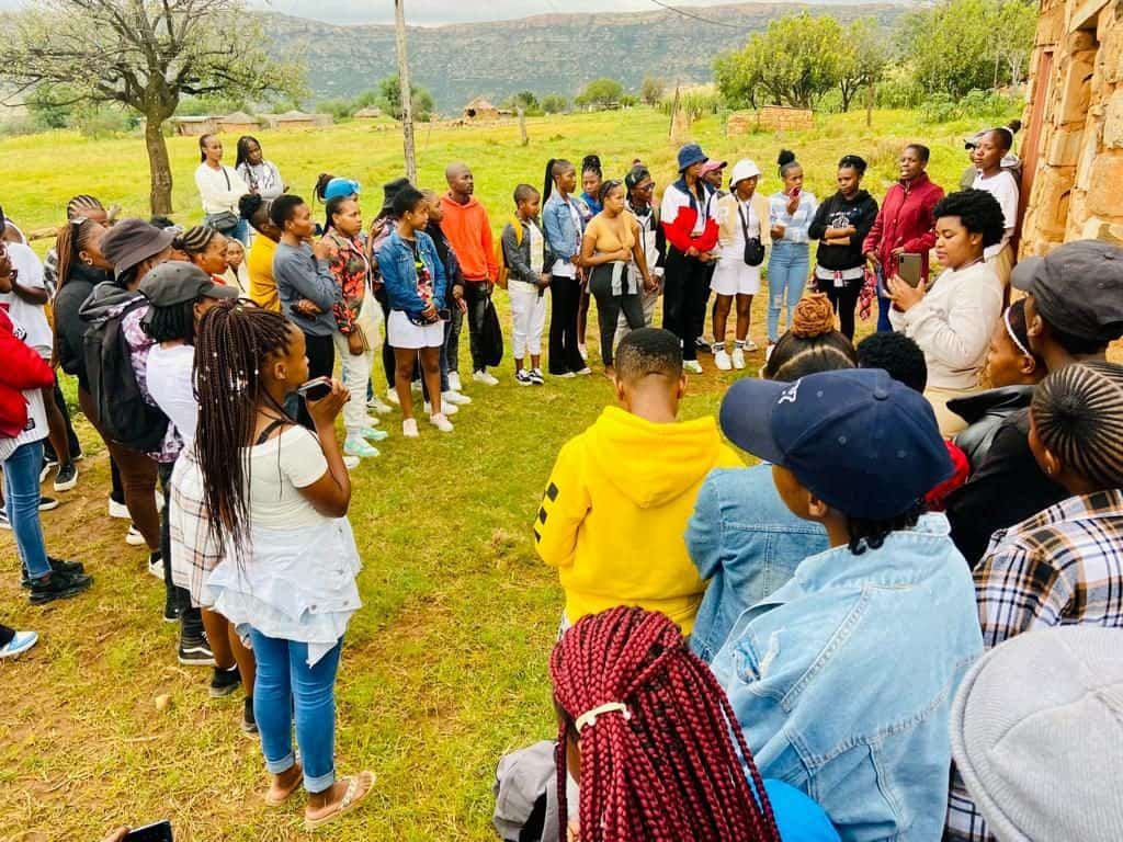 A large group of young people gathered in a circle outdoors in the Makhoarane region
