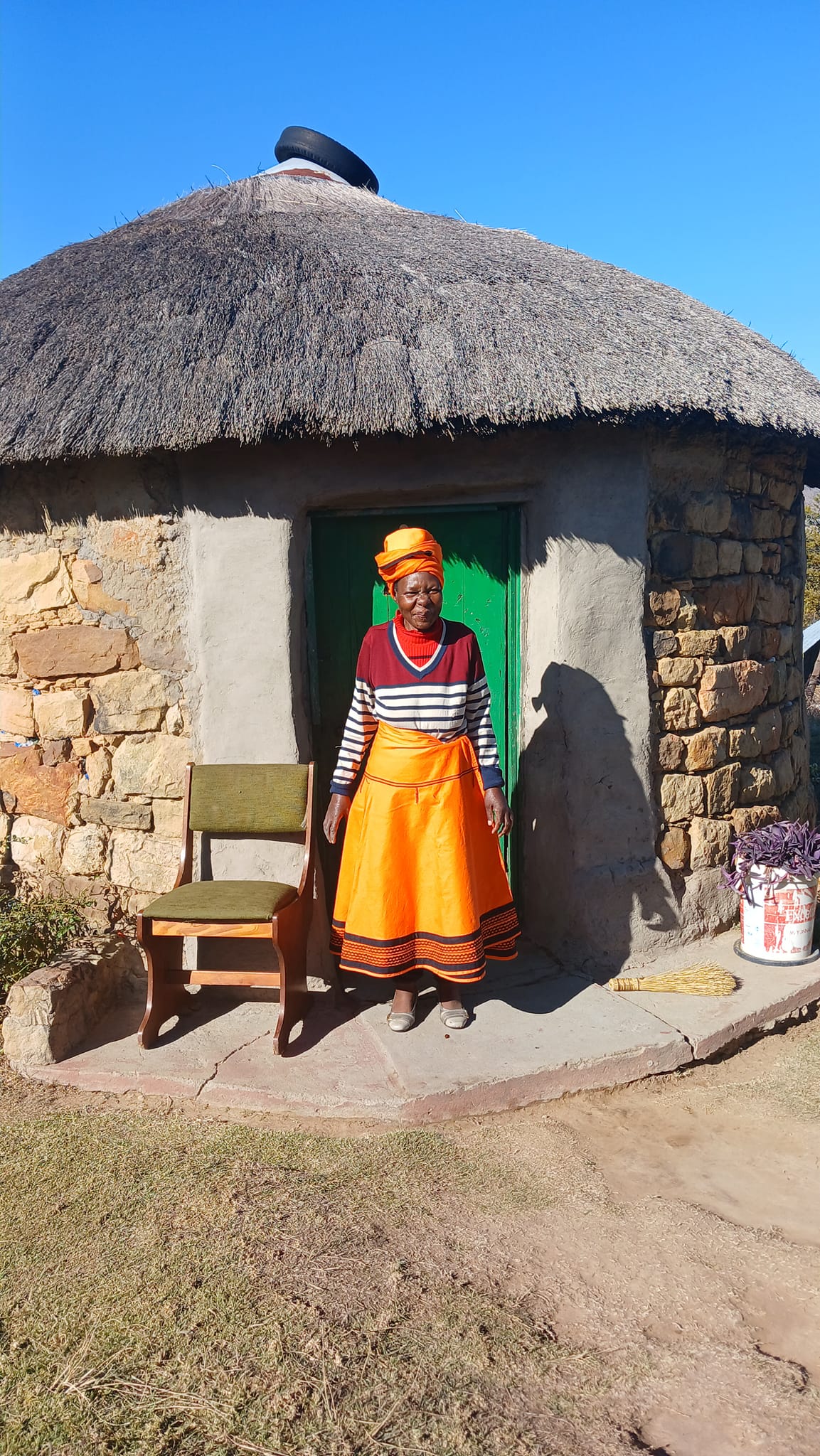 Traditional Basotho rondavel with woman in traditional dress